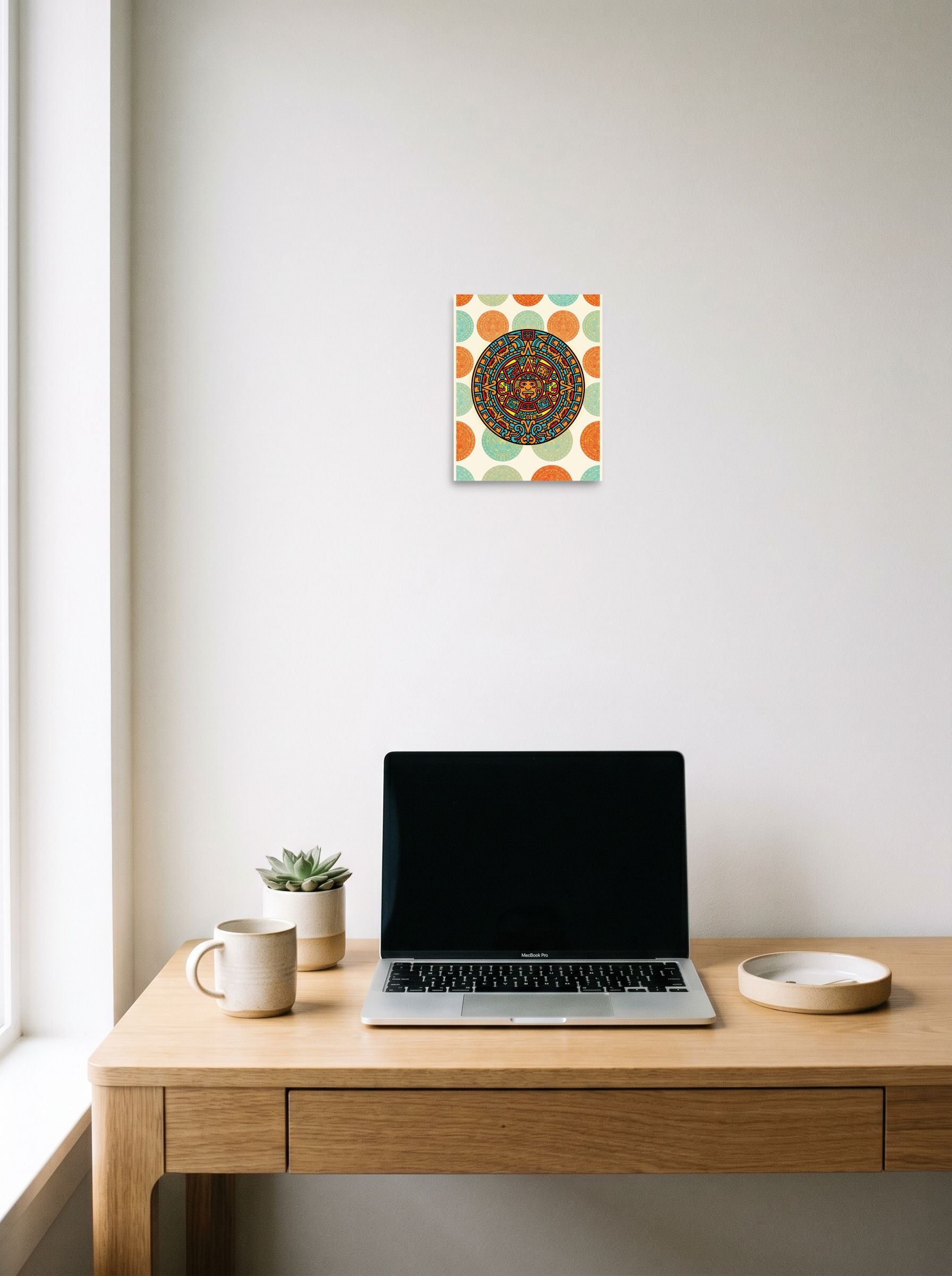 A 8x10 inch unframed paper Pop art print of 'Pop Aztec Sun' hanging above a worktable with a laptop.