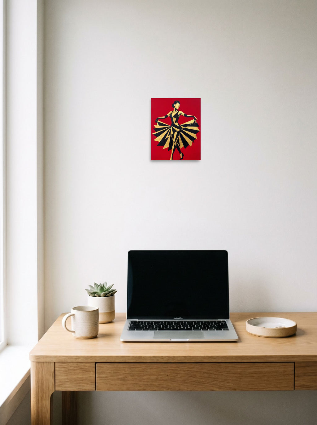 A 8x10 inch unframed paper Art Deco,Cubism print of 'The Golden Dancer' hanging above a worktable with a laptop.