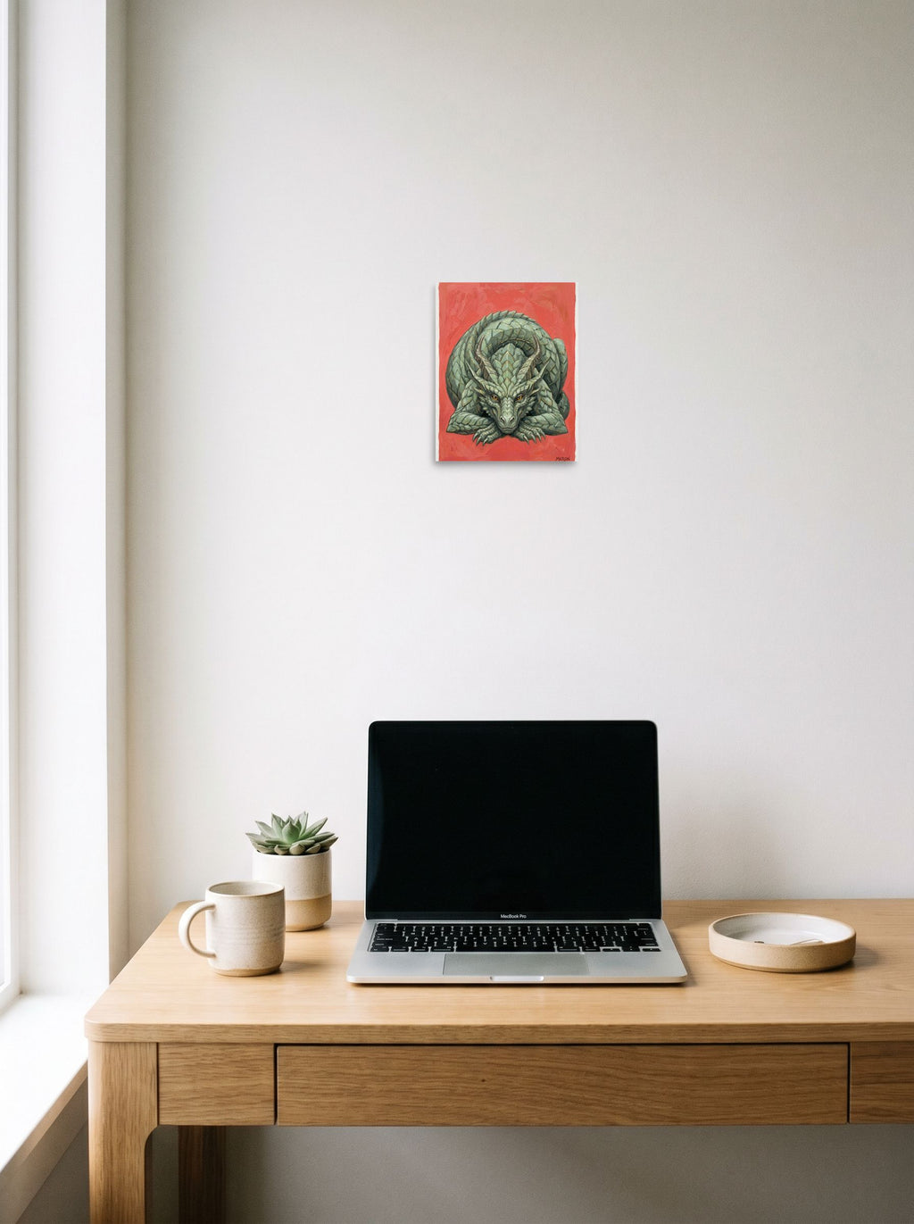 A 8x10 inch unframed paper Fantastic realism print of 'Slumbering Drake' hanging above a worktable with a laptop.
