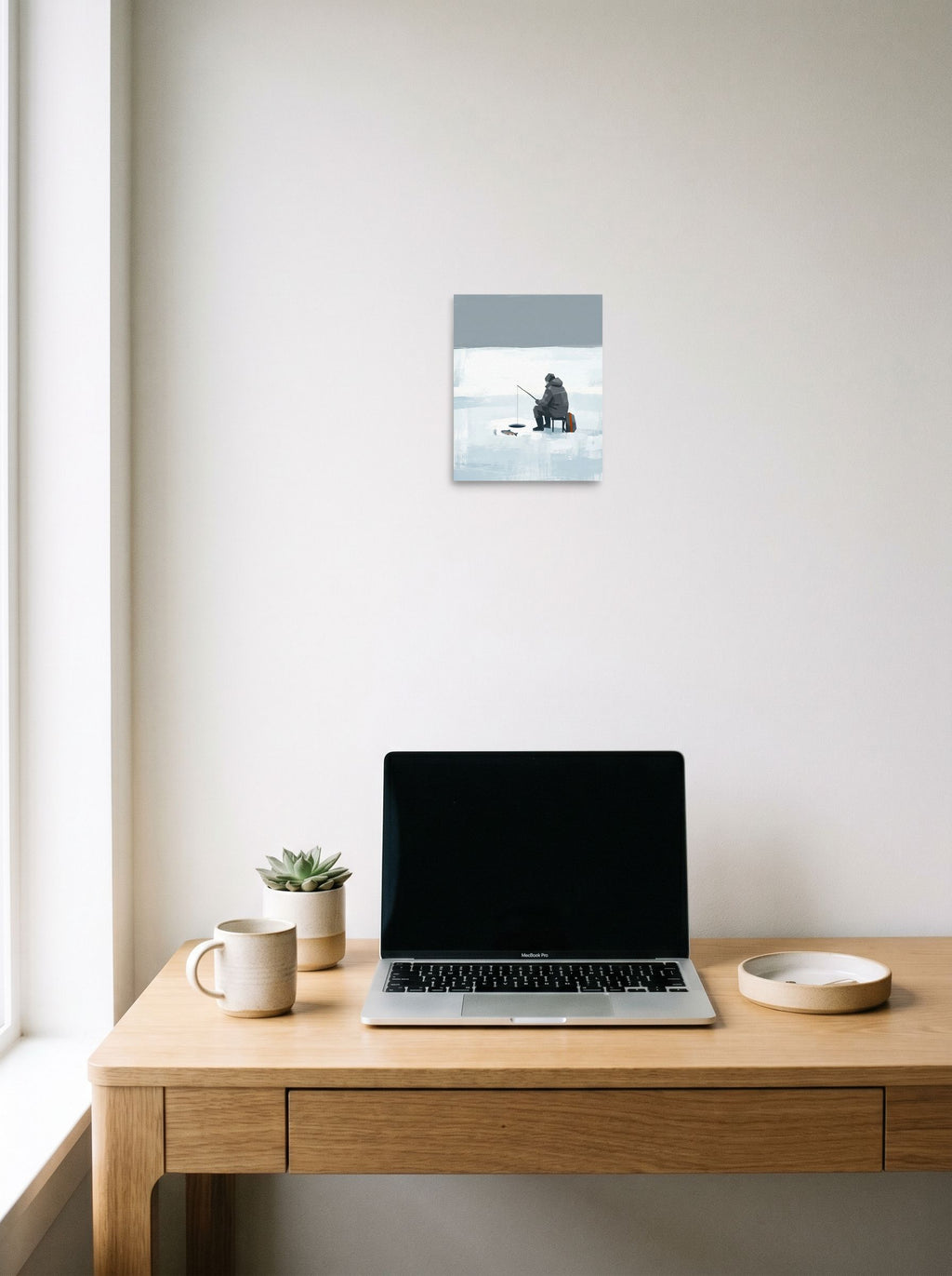 A 8x10 inch unframed paper Minimalism print of 'Winter Solitude' hanging above a worktable with a laptop.