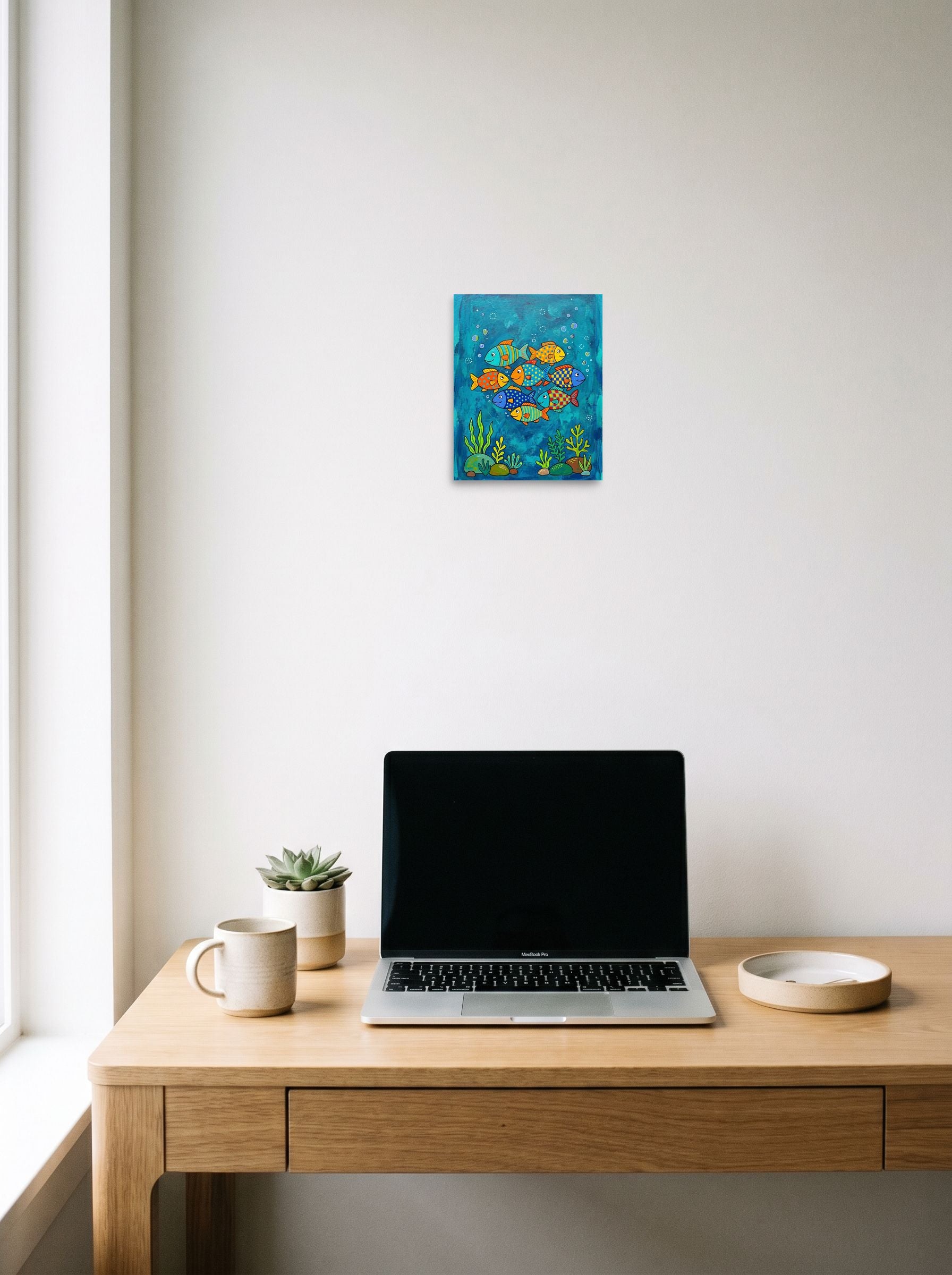 A 8x10 inch unframed paper Naive art print of 'Colorful Ocean Friends' hanging above a worktable with a laptop.